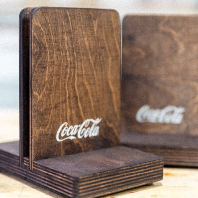 Custom wooden table displays with white printed Coca-Cola logo, designed for restaurant and hospitality branding.